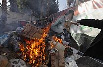A banner of ousted Bashar al-Assad is placed on a fire as rebel forces destroys drugs and alcohol, found at a complex building, in Damascus, Syria, Wednesday, Dec. 25, 2024