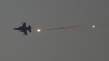 An Israeli fighter jet releases flares as it flies over the Gaza Strip, as seen from southern Israel, 16 January 2024