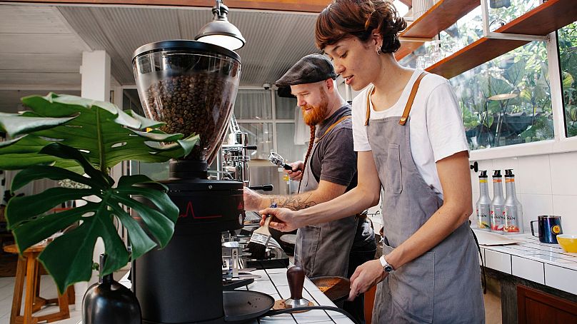 Baristas prepare coffee in machines in a cafe