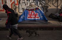 FILE - A man walks past a homeless encampment in downtown Los Angeles, Wednesday, Oct. 25, 2023. (AP Photo/Jae C. Hong, File)