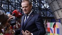 Poland's Prime Minister Donald Tusk speaks with the media prior to a group photo at an EU summit in Brussels.