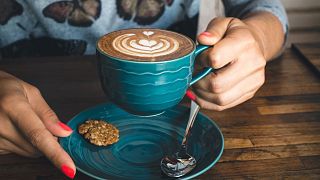 Una persona con in mano una tazza di caffè