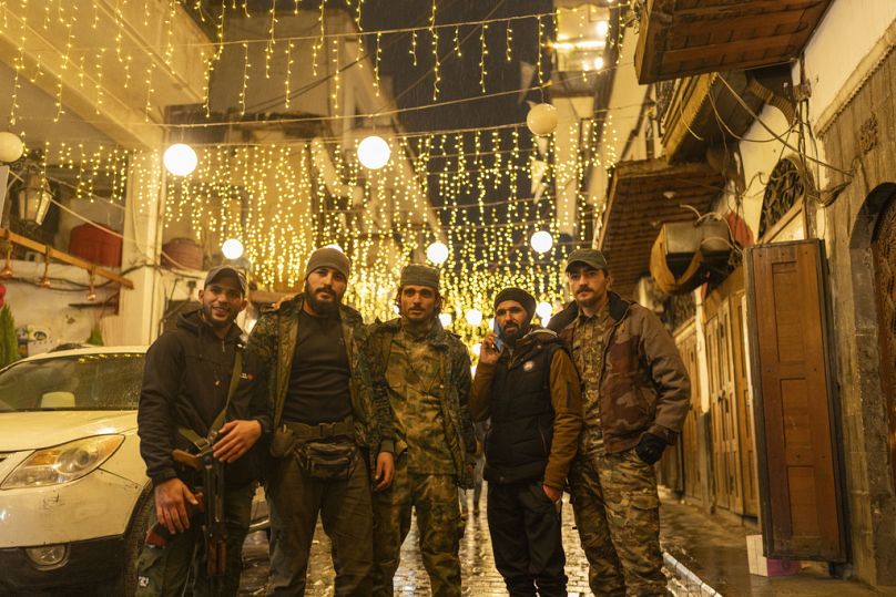 أعضاء من هيئة تحرير الشام التي أطاحت بنظام الأسد يقفون لالتقاط صورة في بلدة دمشق القديمة في سوريا، السبت 28 ديسمبر/كانون الأول 2024