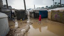 A young girl walks through a flooded street following overnight rainfall at the refugee tent camp for displaced Palestinians in Deir al-Balah, central Gaza Strip