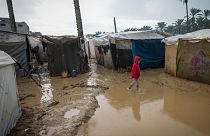 A young girl walks through a flooded street following overnight rainfall at the refugee tent camp for displaced Palestinians in Deir al-Balah, central Gaza Strip