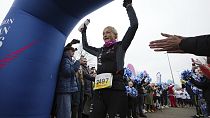 Belgian ultra runner Hilde Dosogne, center, is cheered on as she crosses the finish line during her 366th consecutive marathon in Ghent, Belgium, Tuesday, Dec. 31, 2024