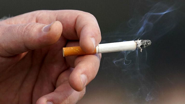 A man holds a lit cigarette while A man holds a lit cigarette while