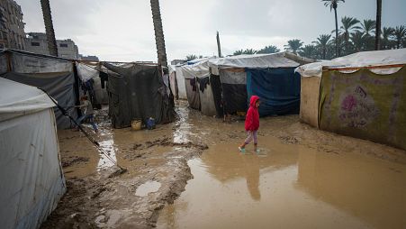 طفلة فلسطينية تسير بين خيام النازحين في دير البلح وسط غزة وقد غمرت مياه الامطار خيامهم 