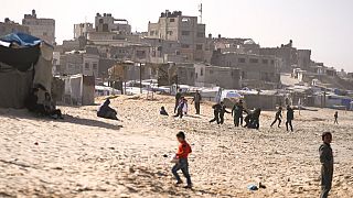 Bambini giocano sulla sabbia in un campo per sfollati palestinesi sul lungomare di Deir al-Balah, nella Striscia di Gaza centrale, venerdì 27 dicembre 2024.