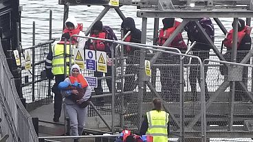 رضيع صغير تحمله امرأة بينما يتم نقل مجموعة من الأشخاص الذين يُعتقد أنهم مهاجرون إلى دوفر، إنجلترا، الأحد، 29 ديسمبر 2024