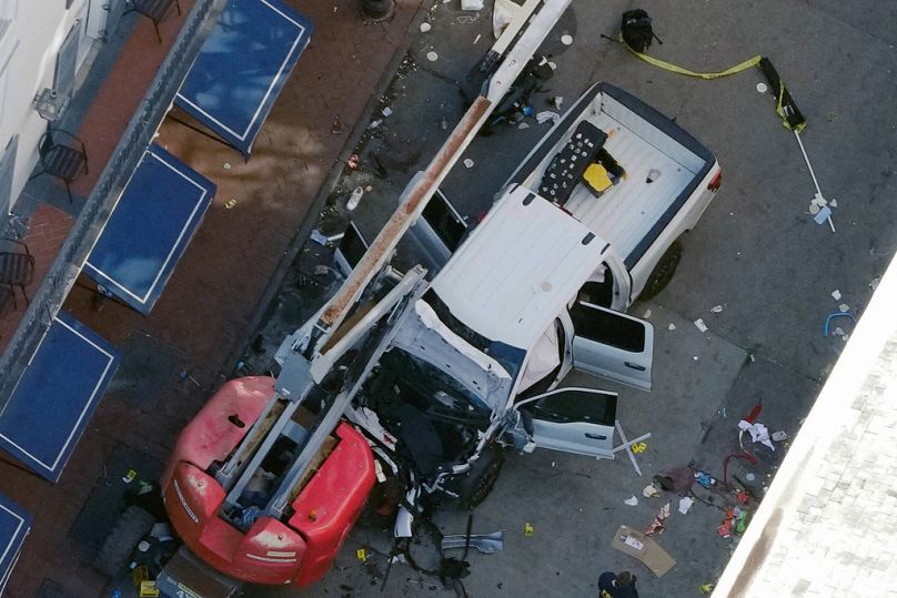 Czarna flaga z białym napisem leży zwinięta na ziemi za pickupem, którym mężczyzna wjechał w tłum na Bourbon Street w Nowym Orleanie, zabijając i raniąc wiele osób