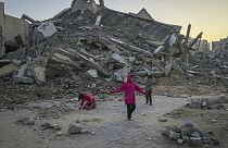 Bambini palestinesi giocano accanto a un edificio distrutto dall'esercito israeliano a Khan Yunis, Striscia di Gaza, 1 gennaio 2025.