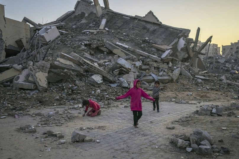Bambini palestinesi giocano accanto a un edificio distrutto dagli attacchi dell'esercito israeliano, Khan Younis, Striscia di Gaza, 1 gennaio 2025