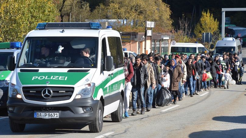 Passau közelében rendőri felvezetéssel kísérik a migránsokat a befogadóközpontba, 2015 októberében