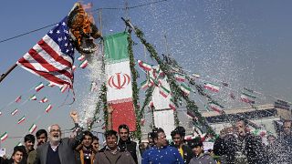 Dimostranti bruciano una bandiera statunitense durante la manifestazione annuale di commemorazione della Rivoluzione islamica iraniana del 1979 a Teheran, l'11 febbraio 2024.