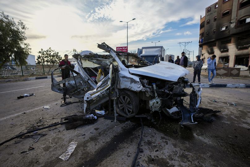 فلسطينيون يتفقدون سيارة استُهدفت بغارة إسرائيلية ليلًا وأودت بحياة ركابها في خان يونس جنوب غزة.