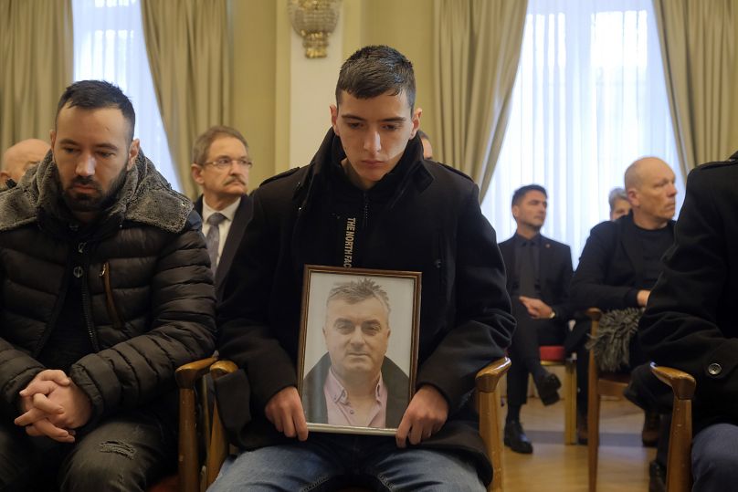 Personas con fotos de familiares en el funeral por las 12 víctimas del tiroteo de Cetinje, 4 de enero de 2025.