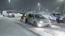 Des personnes aident à pousser des voitures coincées dans la neige à Leeds, en Angleterre, dimanche 5 janvier 2025.