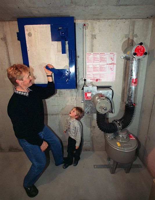 Egy svájci apa mutatja fiának, hogyan záródik a családi bunker bejárata, 2001 novemberében