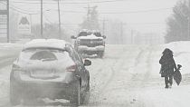 Heavy snow falls as a person walks along U.S. Route 42 in Florence, Ky., Monday, Jan. 6, 2025