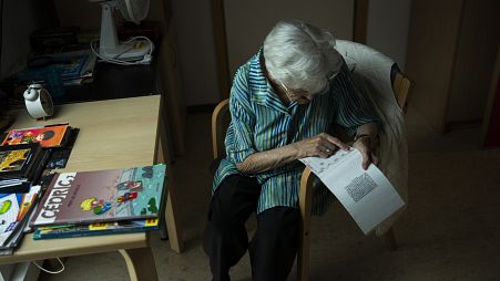 An older women works on a crossword puzzle at a home for elderly people in Belgium in July 2020. 