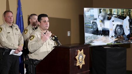 An assistant sheriff shows a photo of the investigation into a Tesla Cybertruck that exploded at a Trump hotel during a press briefing in Las Vegas.