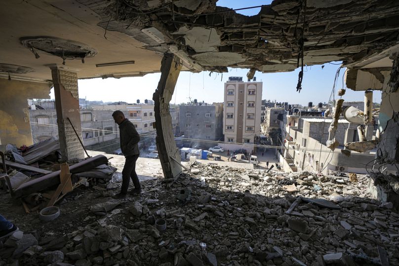 فلسطيني ينظر إلى مبنى سكني متضرر في أعقاب غارة إسرائيلية ليلاً في دير البلح، قطاع غزة، الأربعاء، 8 يناير، 2025. 