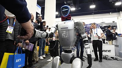 A Unitree H1 robot shakes hands with an attendee at the CES technology show in Las Vegas, 08.01.2025