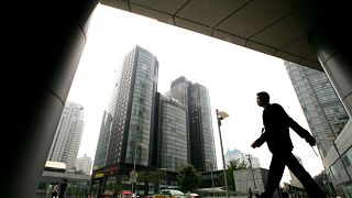 A man walks past new commercial buildings in Beijing.