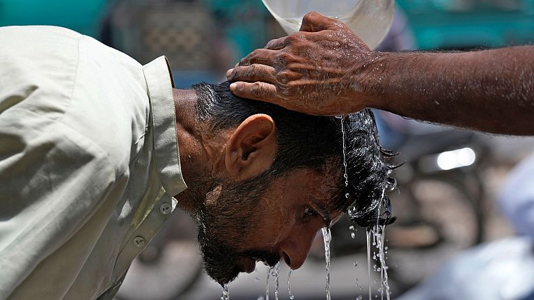 A volunteer pours water to cool a man off during a hot day in Karachi, Pakistan. A volunteer pours water to cool a man off during a hot day in Karachi, Pakistan.