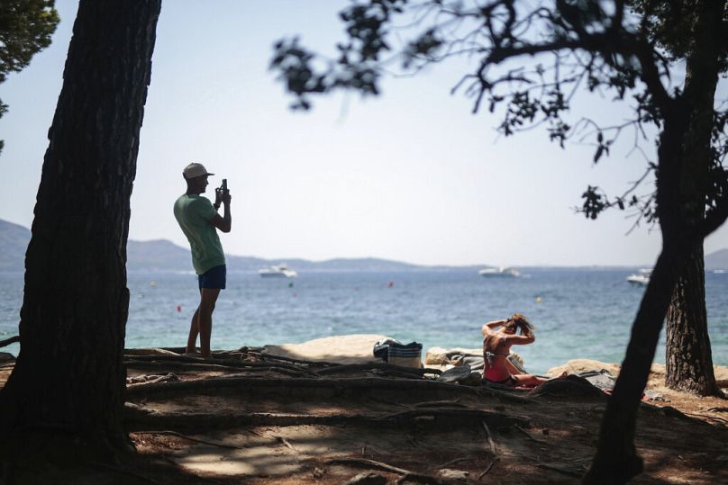 A tourist take photos at the beach in Pollença, in the Balearic Island of Mallorca, Spain, Tuesday, July 28, 2020