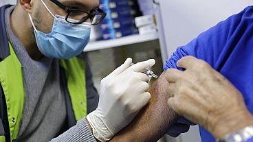 A pharmacist administers a flu vaccine in a Paris drugstore in October 2020. A pharmacist administers a flu vaccine in a Paris drugstore in October 2020.