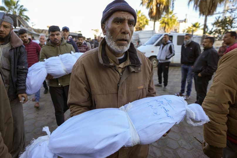 عبد الله أبو لبدة يحمل جثمان ابن أخيه محمد أبو لبدة البالغ من العمر 6 أشهر، في دير البلح ، الجمعة 3 يناير 2025.