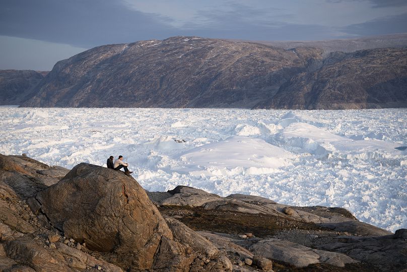 New York University student researchers sit on a rock overlooking the Helheim glacier in Greenland, Aug. 16, 2019. 