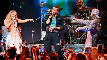 Elyanna, left, and TINI, right, perform with Chris Martin, second from left, and Will Champion of Coldplay on Monday, Oct. 7, 2024
