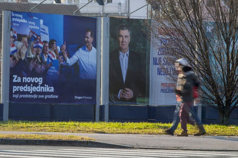 Pedoni passano davanti ai manifesti elettorali dei candidati Dragan Primorac e Zoran Milanovic per le elezioni presidenziali a Zagabria, in Croazia, giovedì 26 dicembre