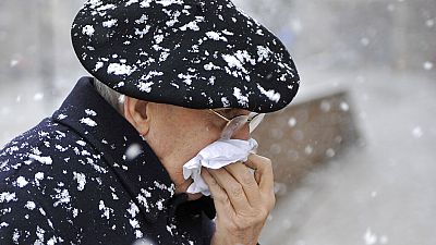 Un homme marche dans la neige en se protégeant le nez de la neige avec un mouchoir à Pampelune, dans le nord de l'Espagne, samedi 7 février 2009.