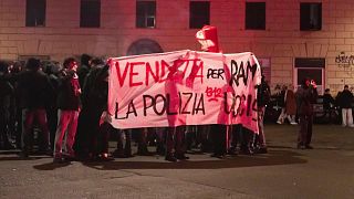 Manifestanti reggono un cartello contro la polizia a Roma