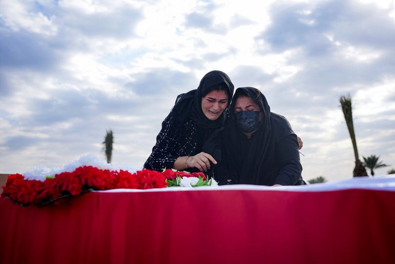 أقارب الإيزيديين يبكون بجانب رفات ذويهم، ضحايا تنظيم "داعش"، خلال مراسم دفن في بغداد بعد استخراجهم من مقبرة جماعية في سنجار، 22 يناير 2024. 