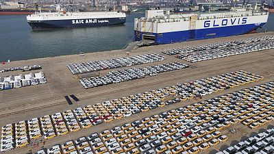 Fahrzeuge und Lastwagen für den Export warten in einem Hafen in Yantai in der ostchinesischen Provinz Shandong auf ihren Transport