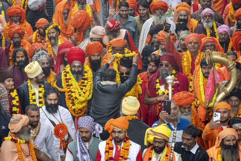 45 günlük Maha Kumbh festivalinden bir gün önce, Prayagraj'da bir dindar, geçit töreninde yürüyen kıdemli bir Hindu din adamına çelenk takıyor.