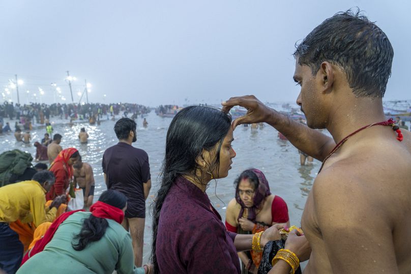 Bir Hindu dindar, Ganj, Yamuna ve efsanevi Saraswati nehirlerinin birleştiği yerde yıkandıktan sonra karısının alnına kırmızı bir işaret koyuyor.