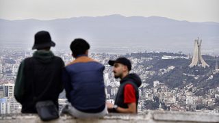 I residenti parlano, con il monumento ai Martiri sullo sfondo, a destra, lunedì 6 gennaio 2025 ad Algeri. 