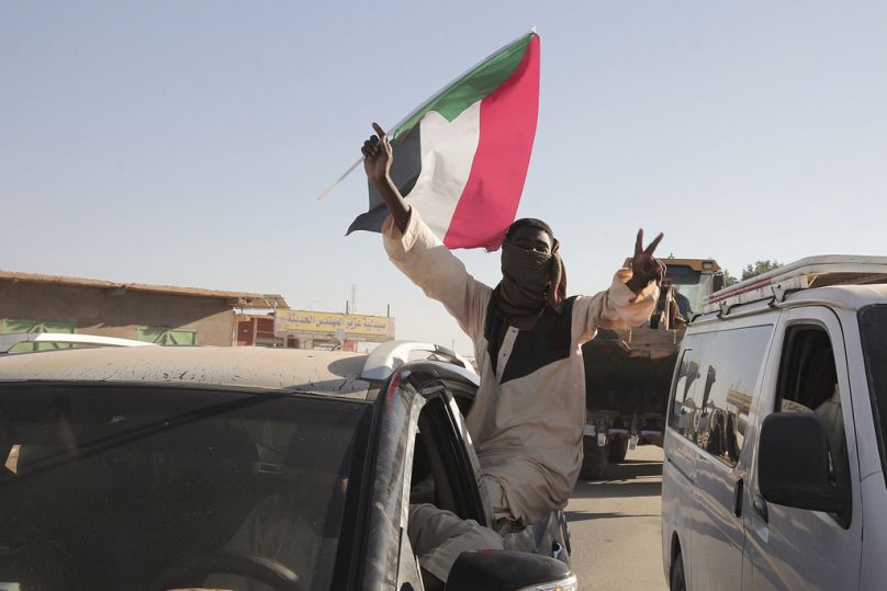 رجل سوداني يلوح بعلم السودان بعد تقارير عن دخول الجيش السوداني إلى مدينة ود مدني وسط البلاد وطرد قوات الدعم السريع، السودان، السبت 11 يناير/كانون الثاني 2025. 