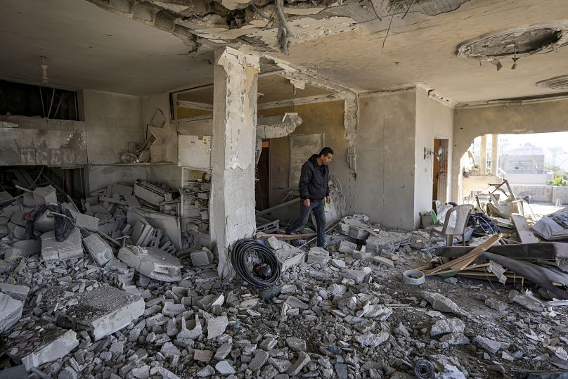 فلسطيني ينظر إلى مبنى سكني متضرر في أعقاب غارة إسرائيلية ليلية في دير البلح، قطاع غزة، الأربعاء، 8 يناير/كانون الثاني 2025
