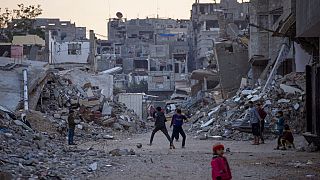 Palestinian children play next to buildings destroyed by Israeli army strikes in Khan Younis, Gaza Strip, Tuesday, Jan. 7, 2025. 