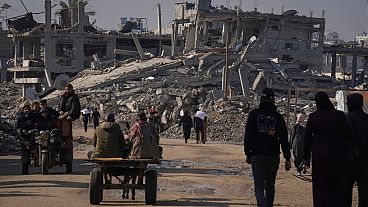 FILE - Palestinians carry U.N.-donated flour in Khan Younis, central Gaza Strip, on Saturday Dec. 14, 2024.