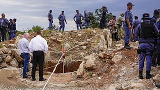 FILE: Agenti di polizia e personale di sicurezza in piedi davanti all'apertura di un pozzo d'oro riformato dove sono intrappolati minatori illegali a Stilfontein, Sudafrica, 15 novembre 2024