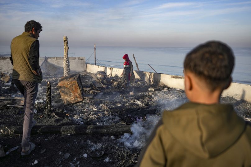 فلسطينيون يفحصون موقع ضربة جوية للجيش الإسرائيلي في دير البلح وسط قطاع غزة، صباح الثلاثاء 14 يناير 2025