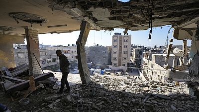 FILE: A Palestinian looks at a damaged residential building following an overnight Israeli strike in Deir al-Balah, Gaza Strip, 8 January 2025